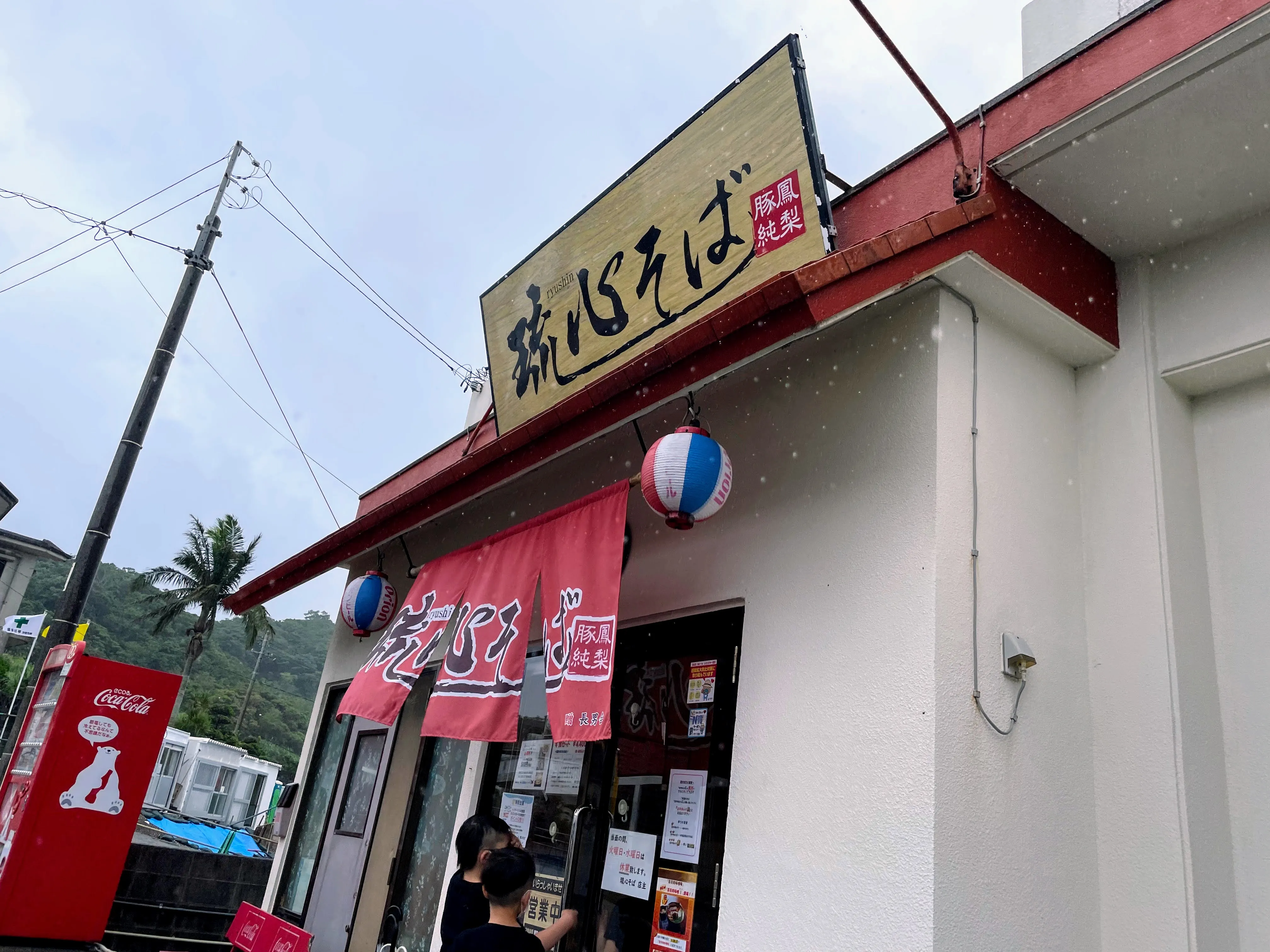 琉心そばの外観。赤い暖簾とオリオンビールの提灯が目印