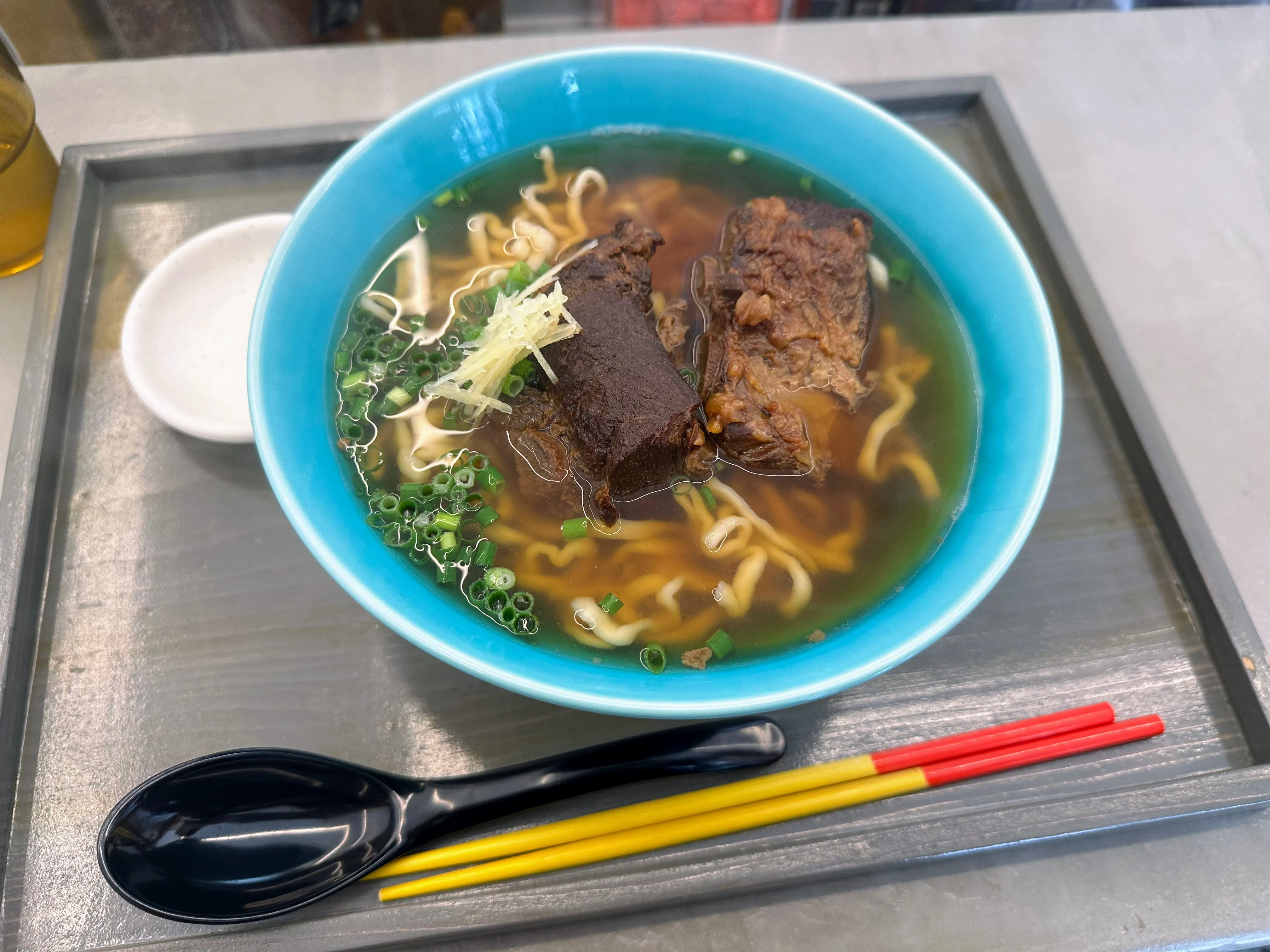 OKINAWA SOBA EIBUNのソーキそば。青い丼にソーキとしょうが、小ねぎがのっている